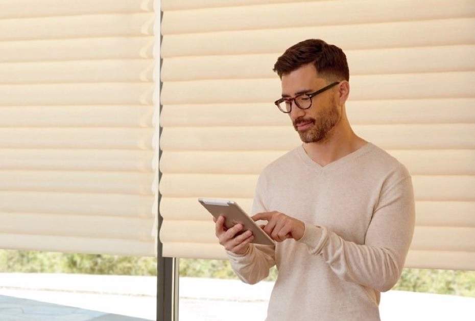 left-What Are Motorized Shades_ man holding device to control shades